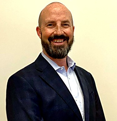 Colin Futrelle, smiling, wearing a navy blazer and light blue button-down shirt
